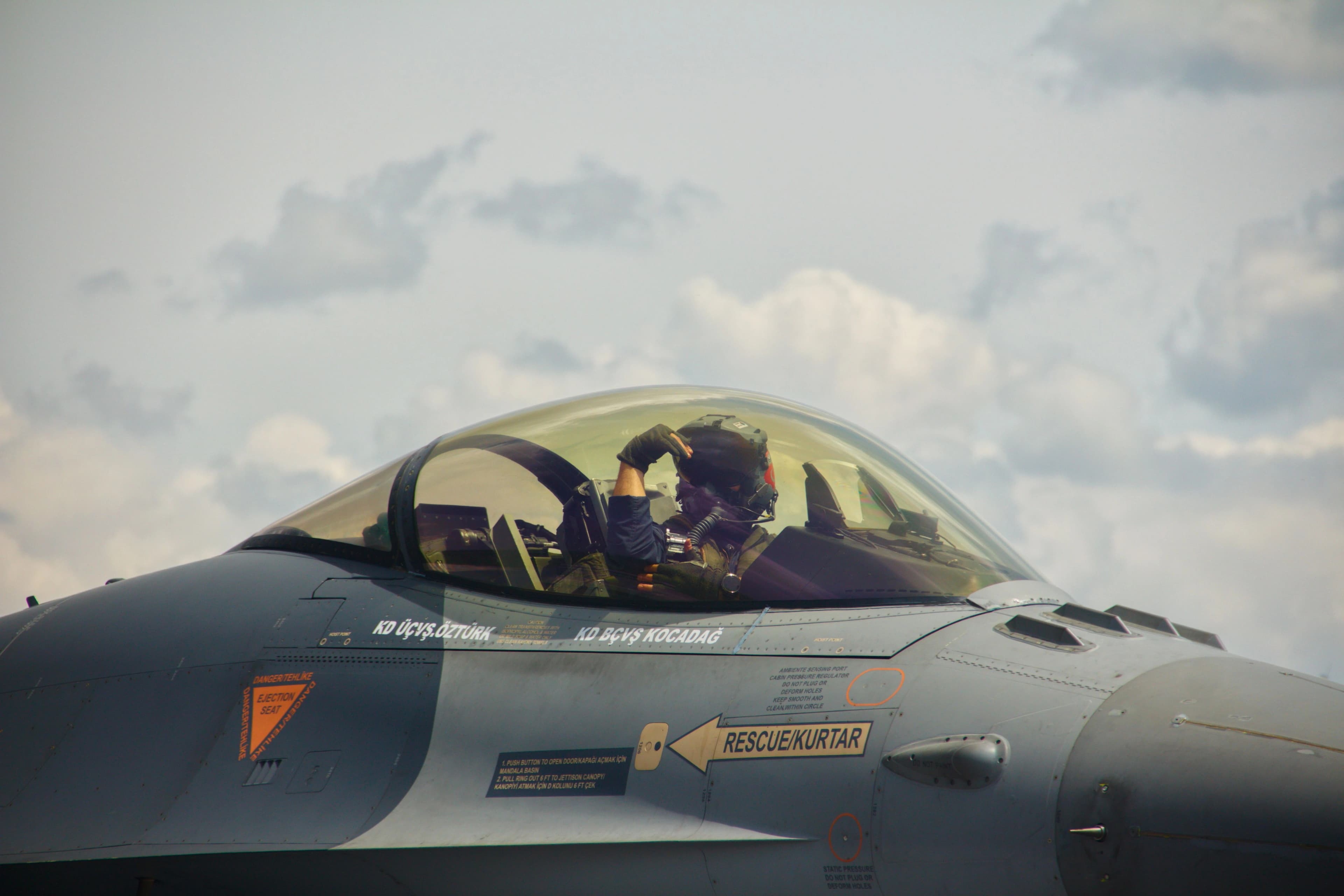 a military pilot sits in the cockpit of a fighter jet