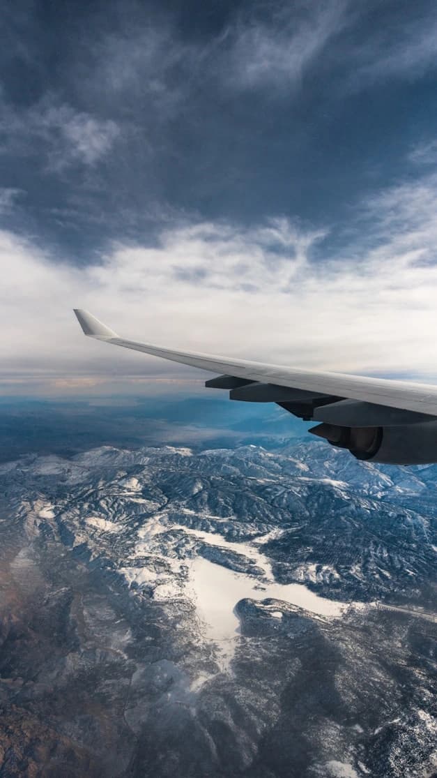 Airplane wing cutting through clouds during flight