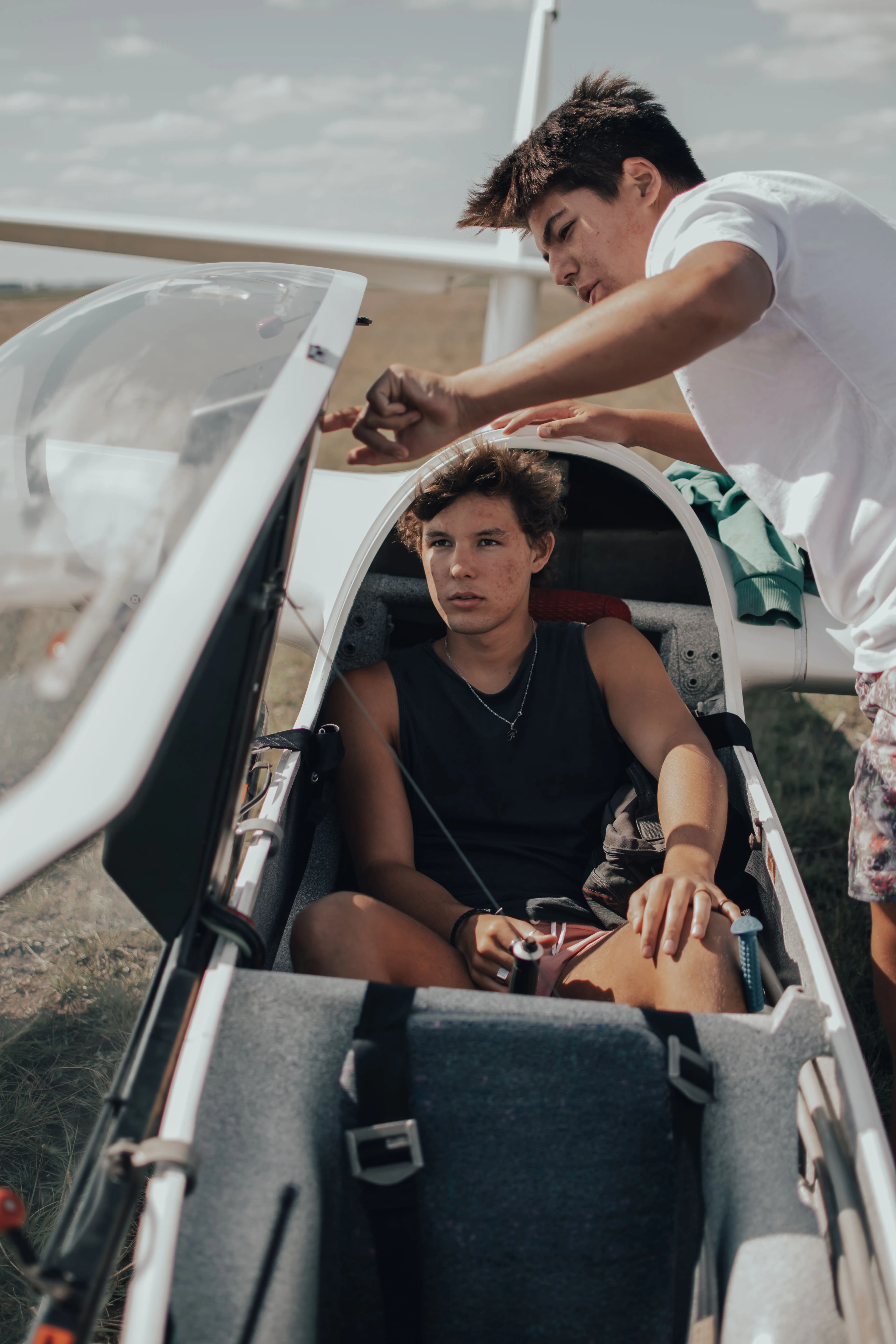 two young students preparing a glider for flight under sunny skies, teamwork and adventure
